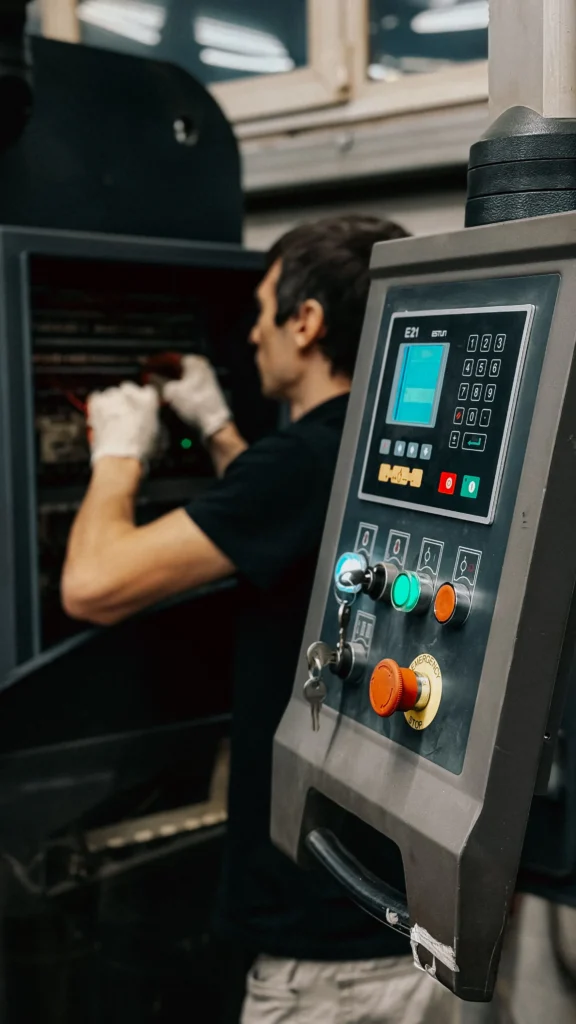 Why Businesses Are Moving From Sage 200 To Microsoft Dynamics 365 Business Central Factory Technician Using An Industrial Control Panel To Manage Manufacturing Machinery