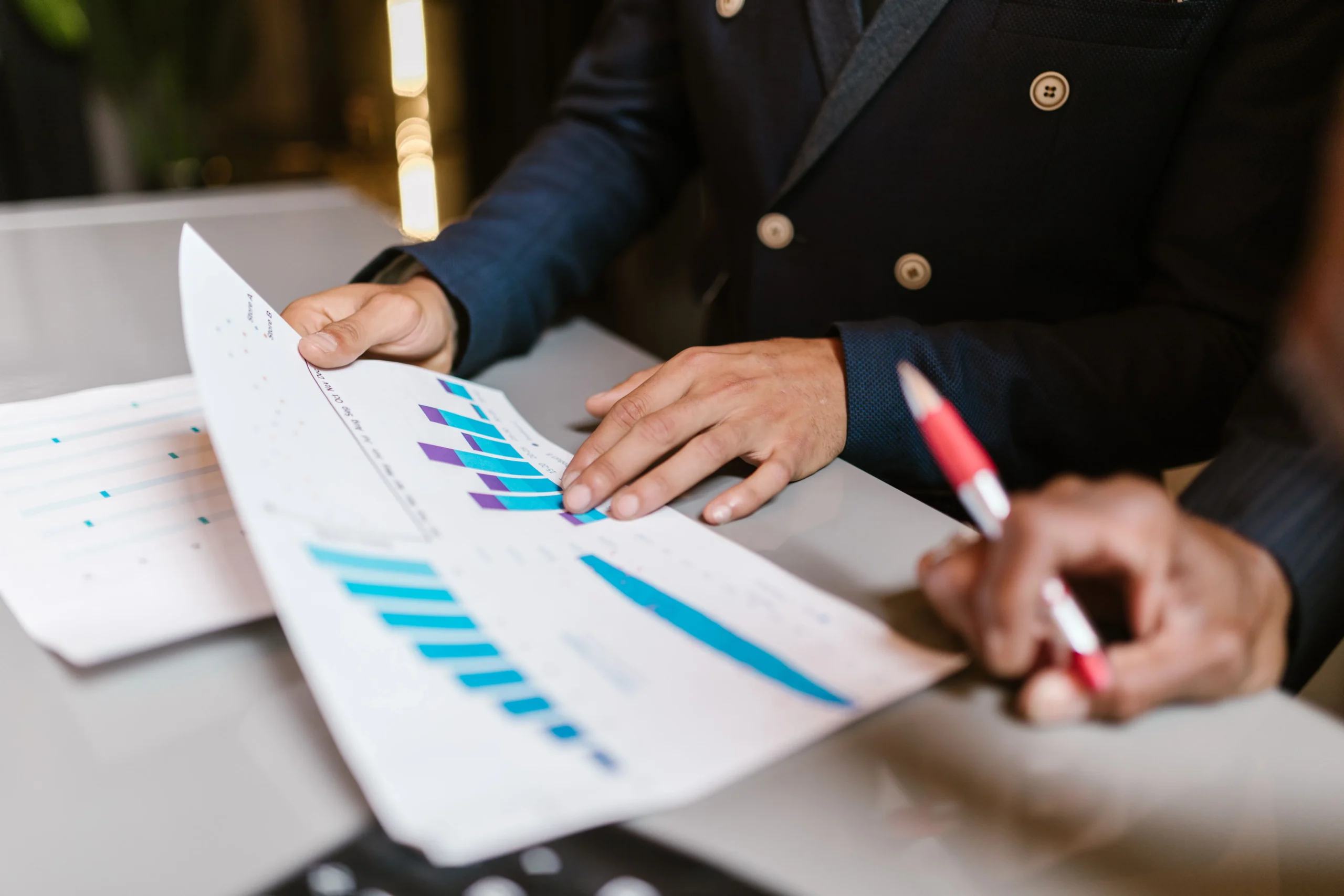 What Is Manufacturing Erp Software And How Is It Different From Mrp? Close-Up Of Colleagues Reviewing Printed Financial Charts And Graphs During A Business Meeting